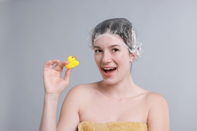 Photo of Woman with shower cap and bath duck on grey background