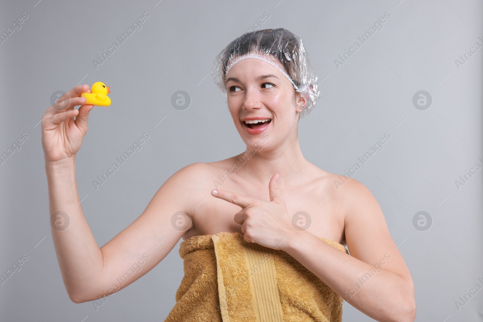 Photo of Woman with shower cap and bath duck on grey background