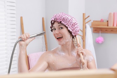 Photo of Woman with cap and brush taking shower in bathroom