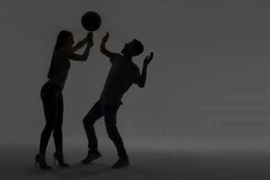 Domestic violence. Silhouette of woman with frying pan threatening her husband on grey background