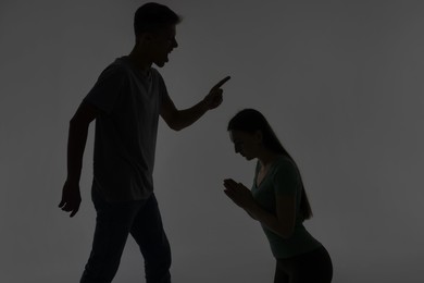 Photo of Domestic violence. Silhouette of man threatening his wife on grey background