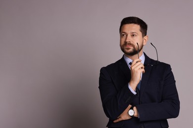 Portrait of banker with glasses on grey background, space for text