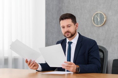 Photo of Banker working with documents at wooden table in office