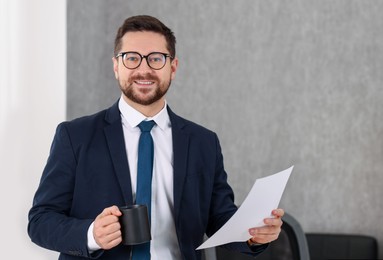 Photo of Banker with document and cup of drink in office