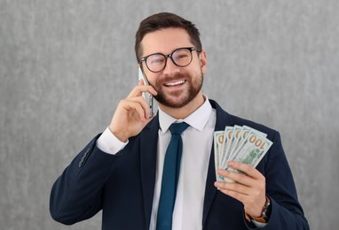 Photo of Banker with dollar banknotes talking on smartphone in office