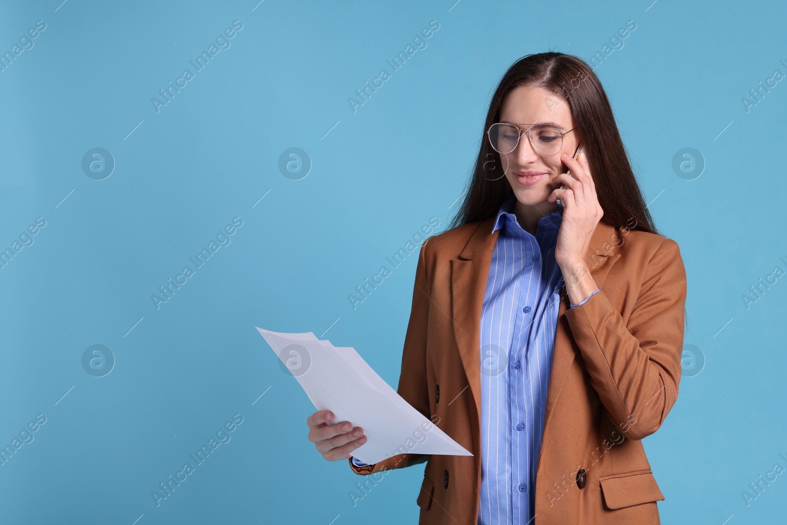 Photo of Banker with documents talking on smartphone against light blue background, space for text