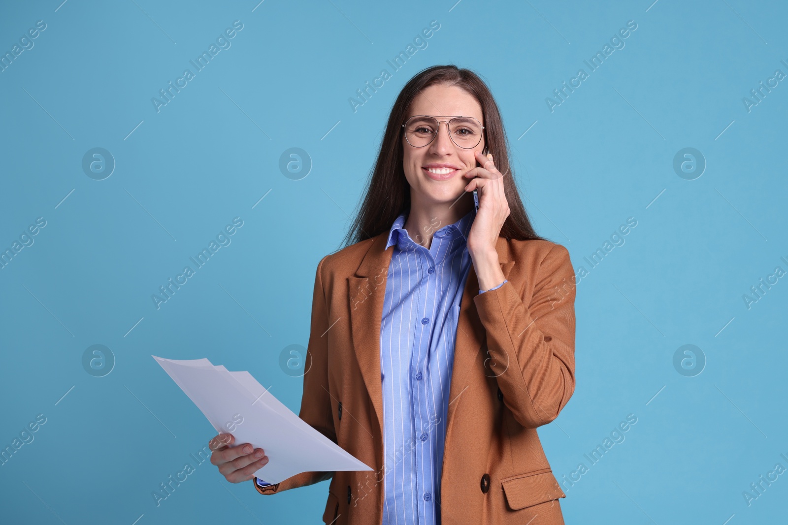 Photo of Banker with documents talking on smartphone against light blue background