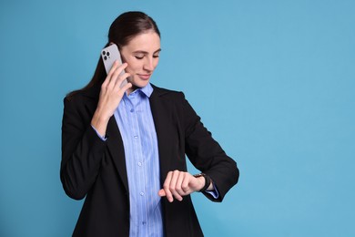 Photo of Banker checking time while talking on smartphone against light blue background, space for text