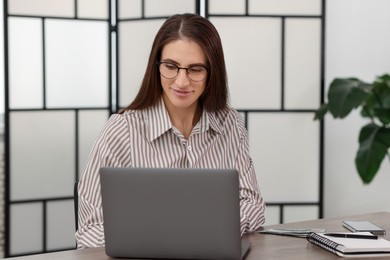 Photo of Banker working with laptop at wooden table in office