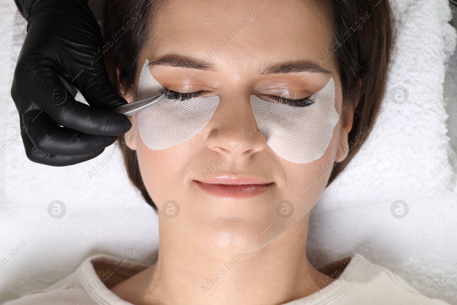 Photo of Woman undergoing lash extensions procedure in beauty salon, top view