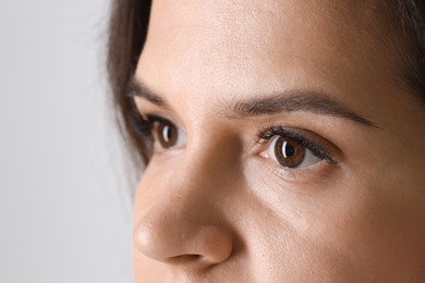 Photo of Woman with beautiful long eyelashes on light background, closeup. Eyelash extension procedure