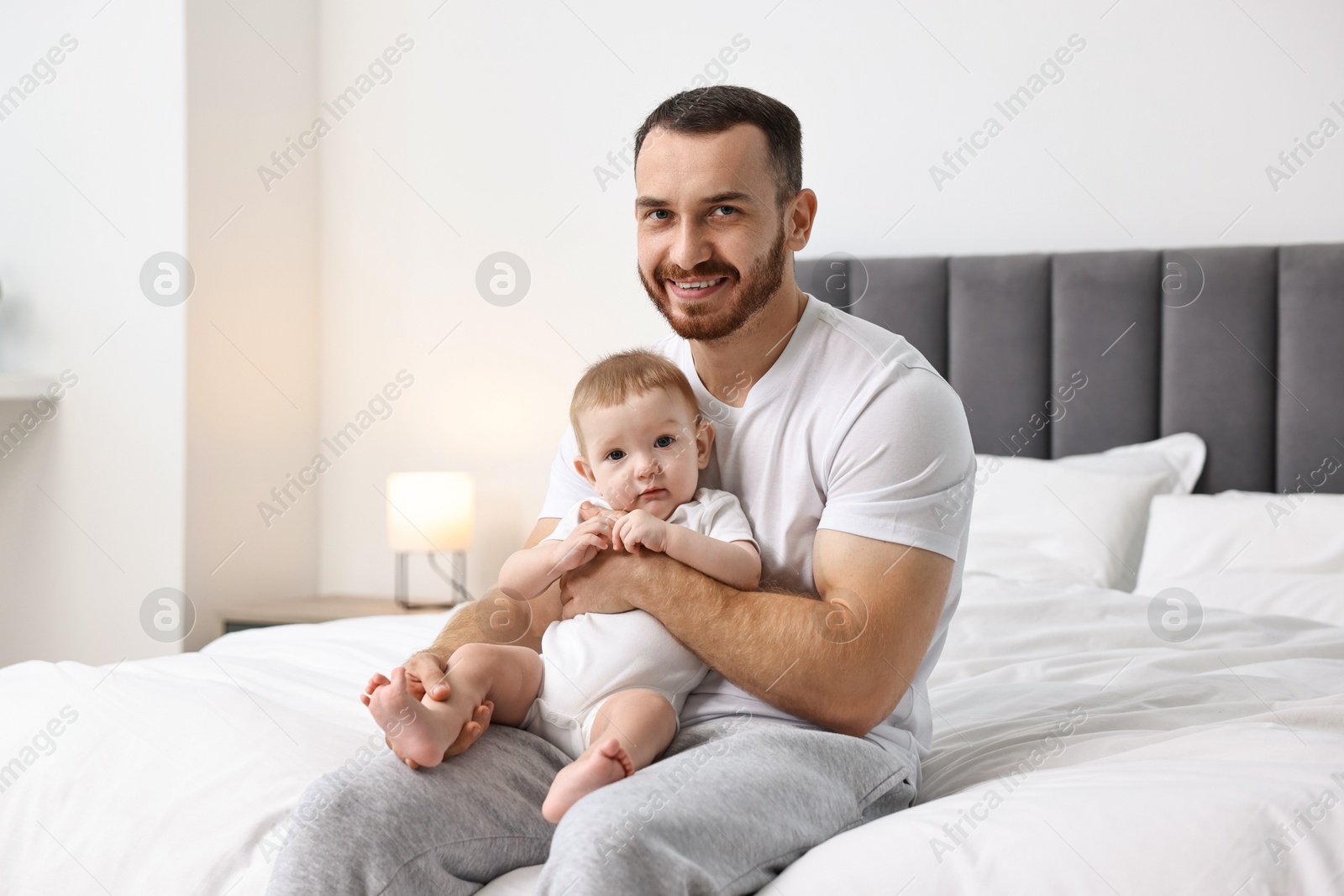 Photo of Father with his little baby on bed at home. Space for text