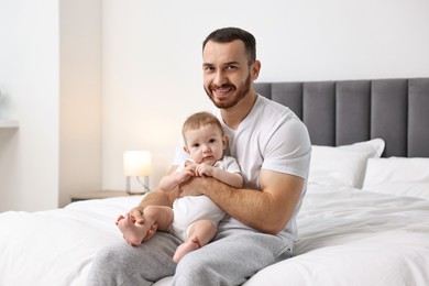 Father with his little baby on bed at home. Space for text