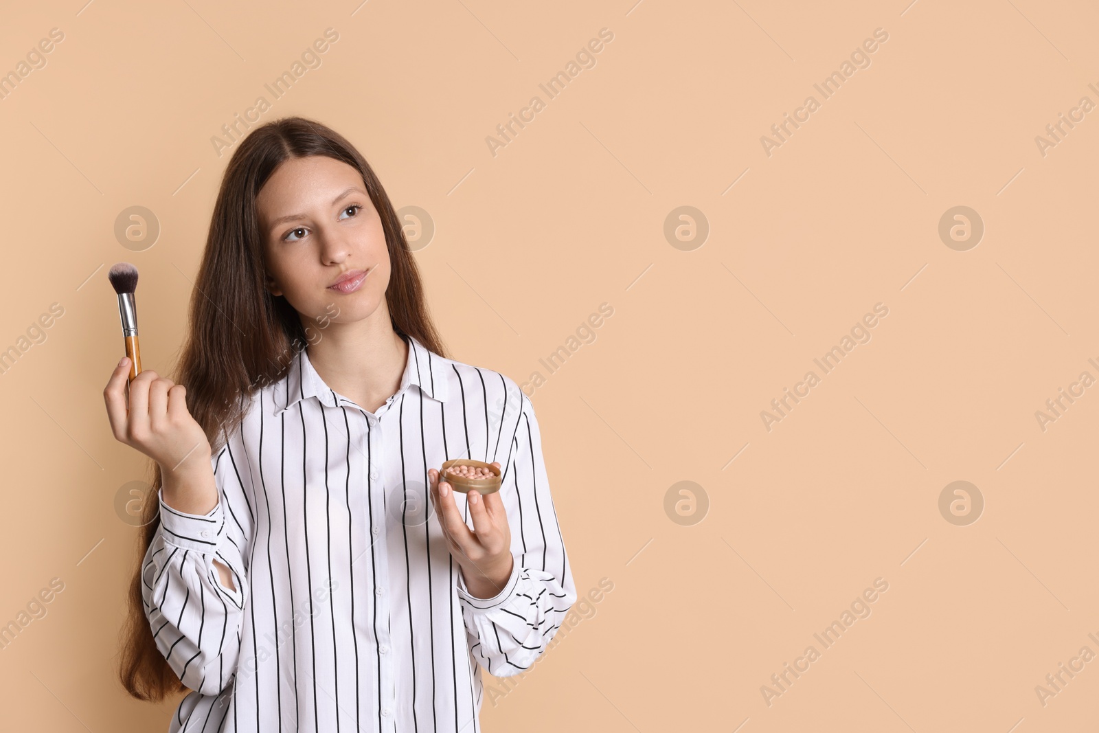 Photo of Teenage girl with blusher and makeup brush on beige background. Space for text