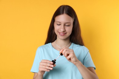 Photo of Smiling teenage girl with lip gloss on yellow background