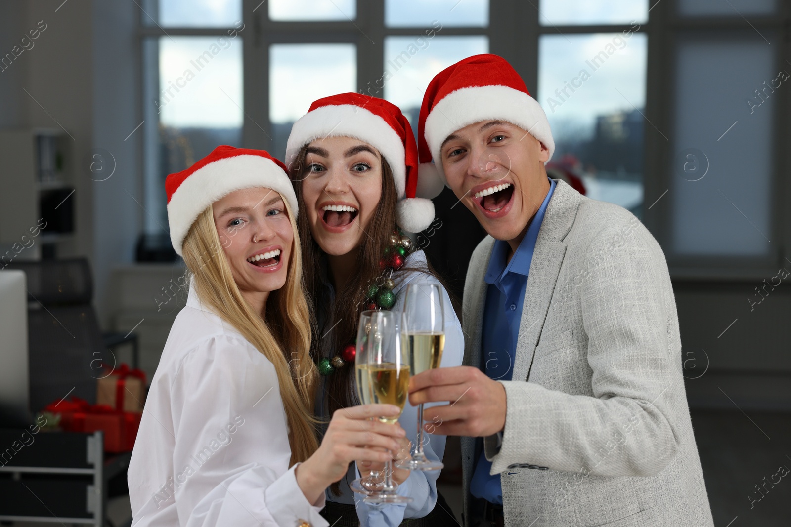 Photo of Happy coworkers clinking glasses of wine during office Christmas party