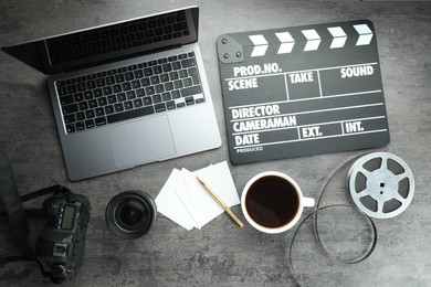 Photo of Flat lay composition with movie clapper, film reel and camera lens on grey textured table