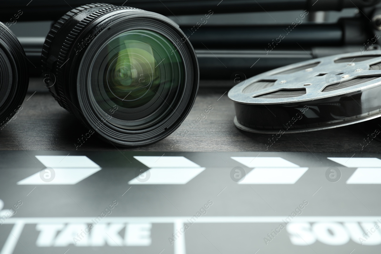 Photo of Movie clapper, film reel and camera lens on table, closeup