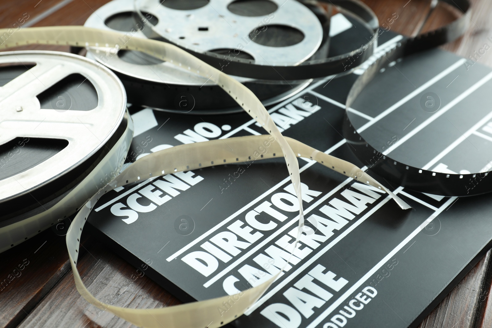 Photo of Movie clapper and film reels on wooden table, closeup