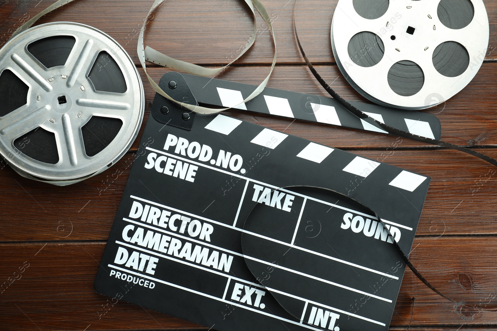 Photo of Movie clapper and film reels on wooden table, flat lay