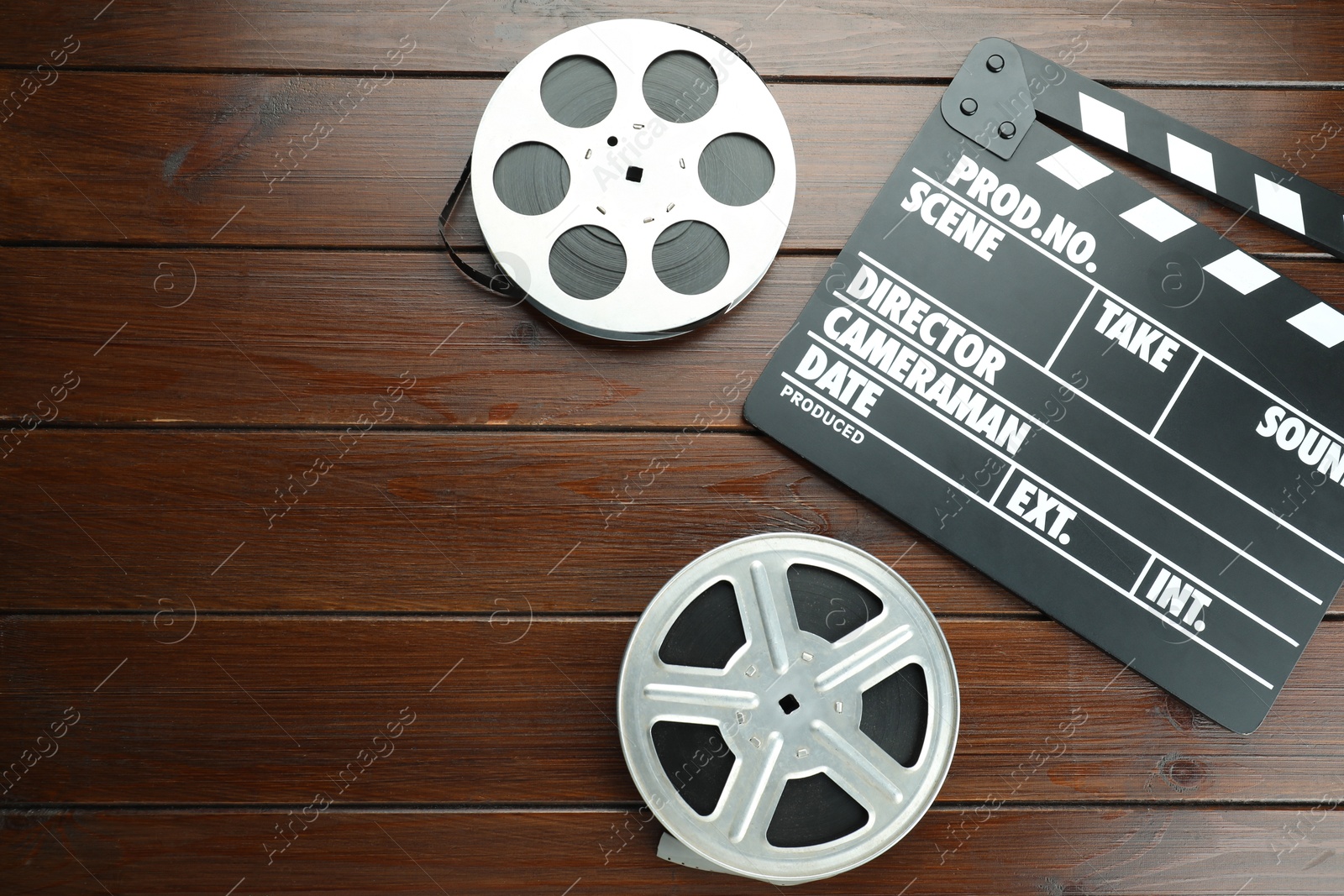 Photo of Movie clapper and film reels on wooden table, flat lay. Space for text