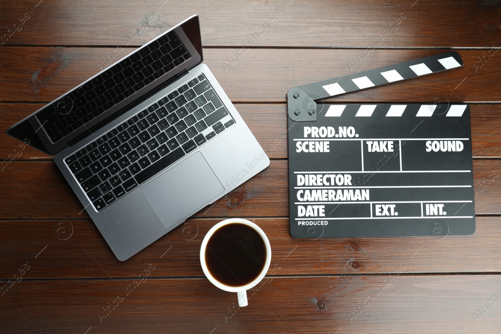 Photo of Movie clapper, laptop and coffee on wooden table, flat lay