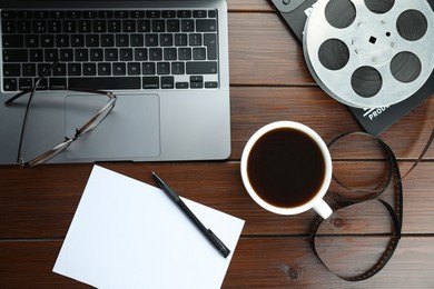 Photo of Flat lay composition with movie clapper, film reel and laptop on wooden table