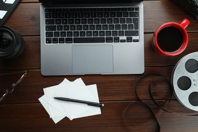 Photo of Flat lay composition with laptop, film reel and camera lens on wooden table