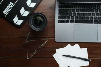 Photo of Flat lay composition with movie clapper, film reel and laptop on wooden table