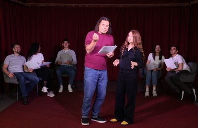 Professional actors with their scripts rehearsing in theatre