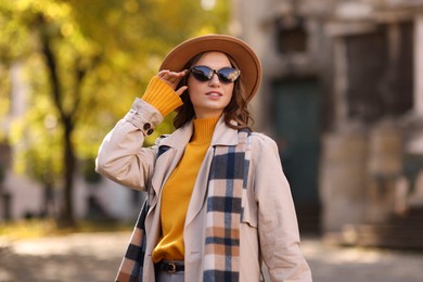 Charming young woman in stylish outfit on city street. Autumn season