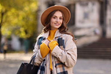 Charming young woman in stylish outfit on city street. Autumn season