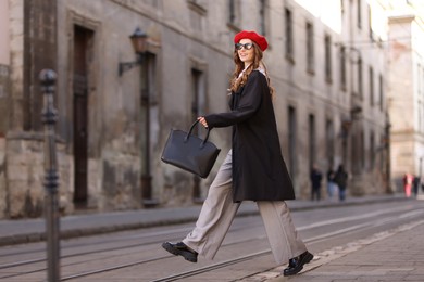 Photo of Charming young woman in stylish outfit on city street. Autumn season