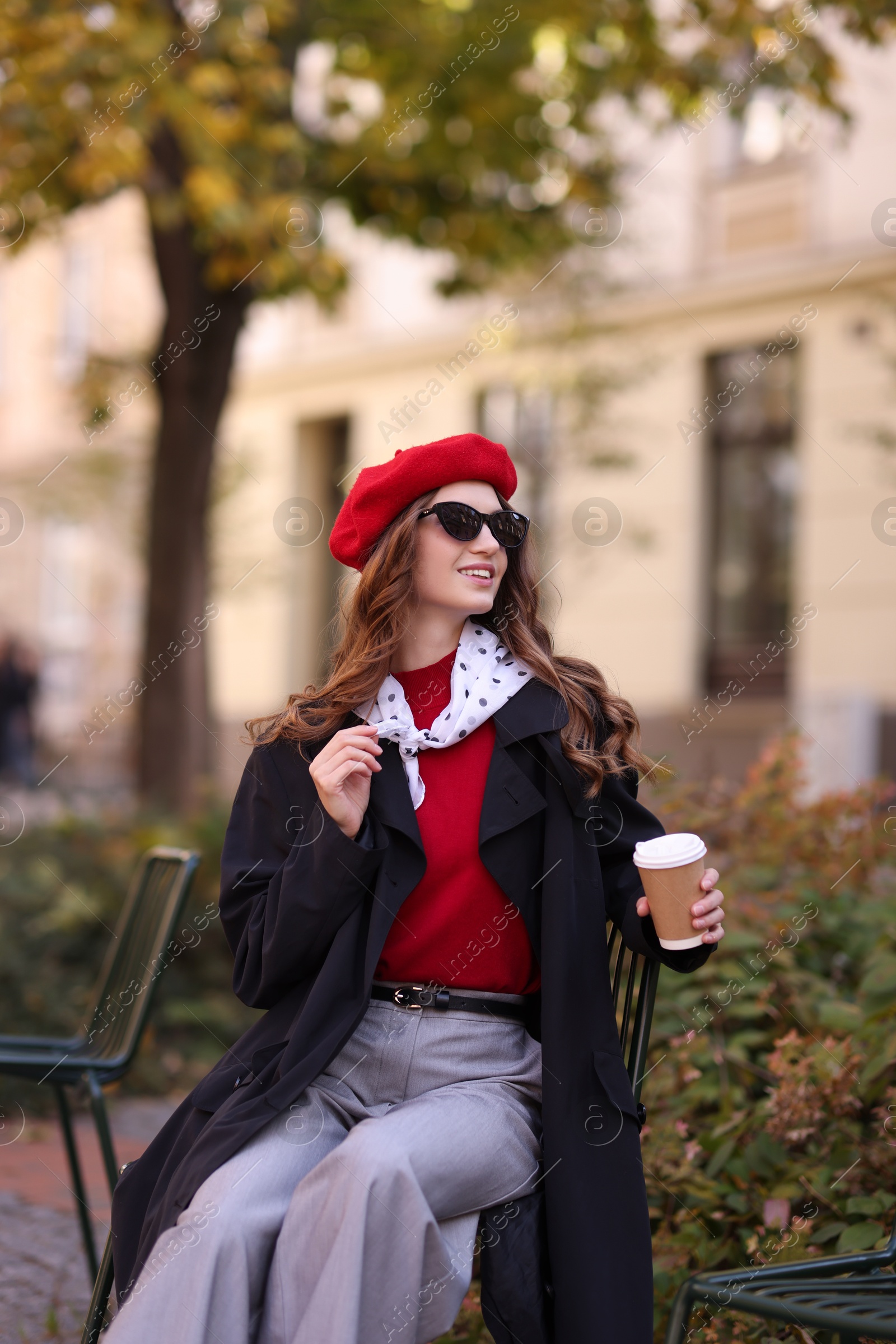 Photo of Stylish woman with cup of hot drink outdoors