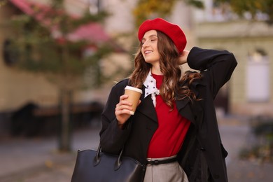 Photo of Stylish woman with cup of hot drink outdoors