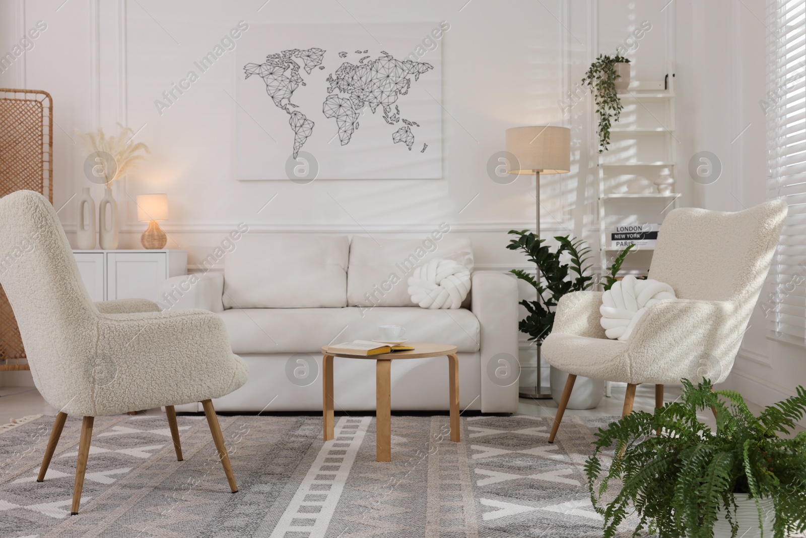 Photo of Soft armchairs, coffee table, sofa and houseplants in room