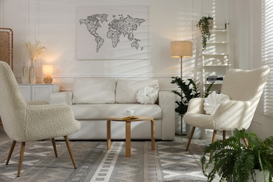 Photo of Soft armchairs, coffee table, sofa and houseplants in room