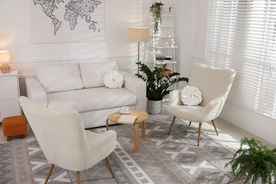 Photo of Soft armchairs, coffee table, sofa and green houseplants in room