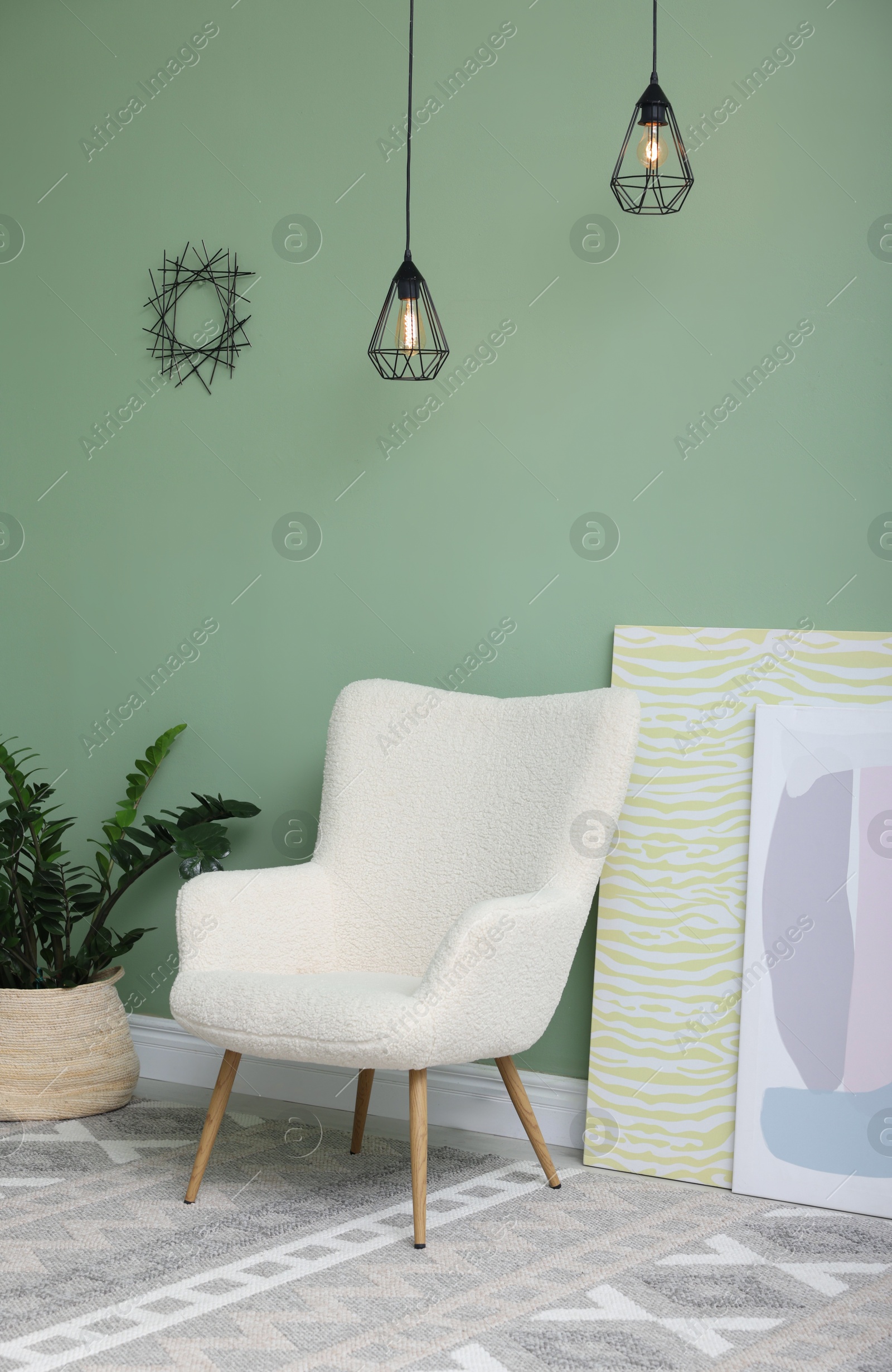 Photo of Soft armchair, green houseplant and pictures in room