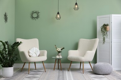 Photo of Soft armchairs, side table and folding screen in room