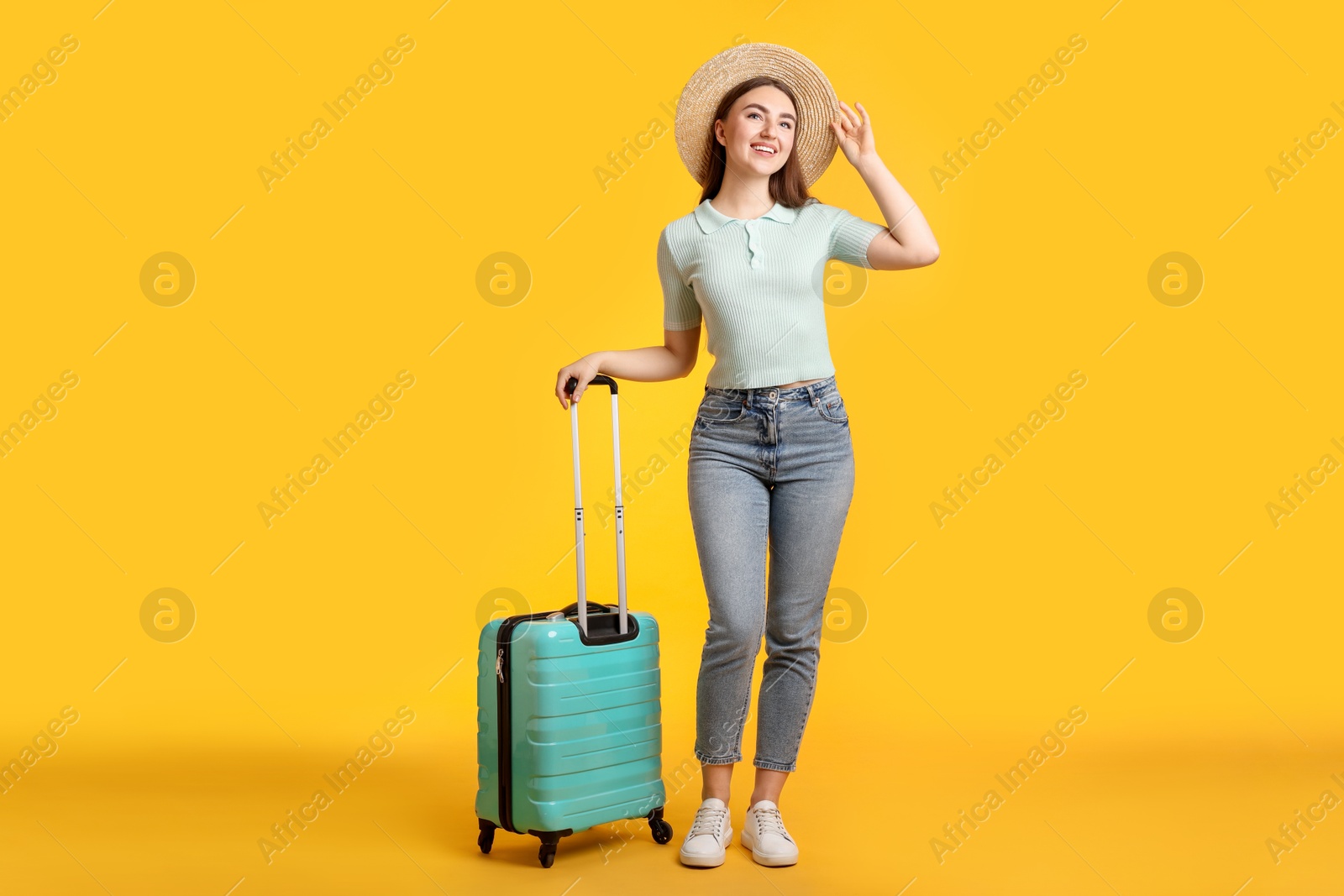 Photo of Woman in straw hat with suitcase on orange background