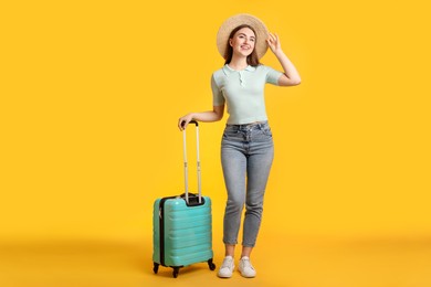 Photo of Woman in straw hat with suitcase on orange background