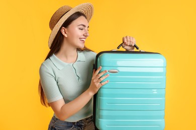 Photo of Woman in straw hat with suitcase on orange background