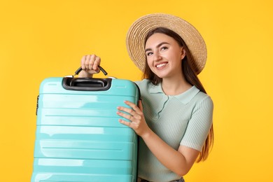 Photo of Woman in straw hat with suitcase on orange background