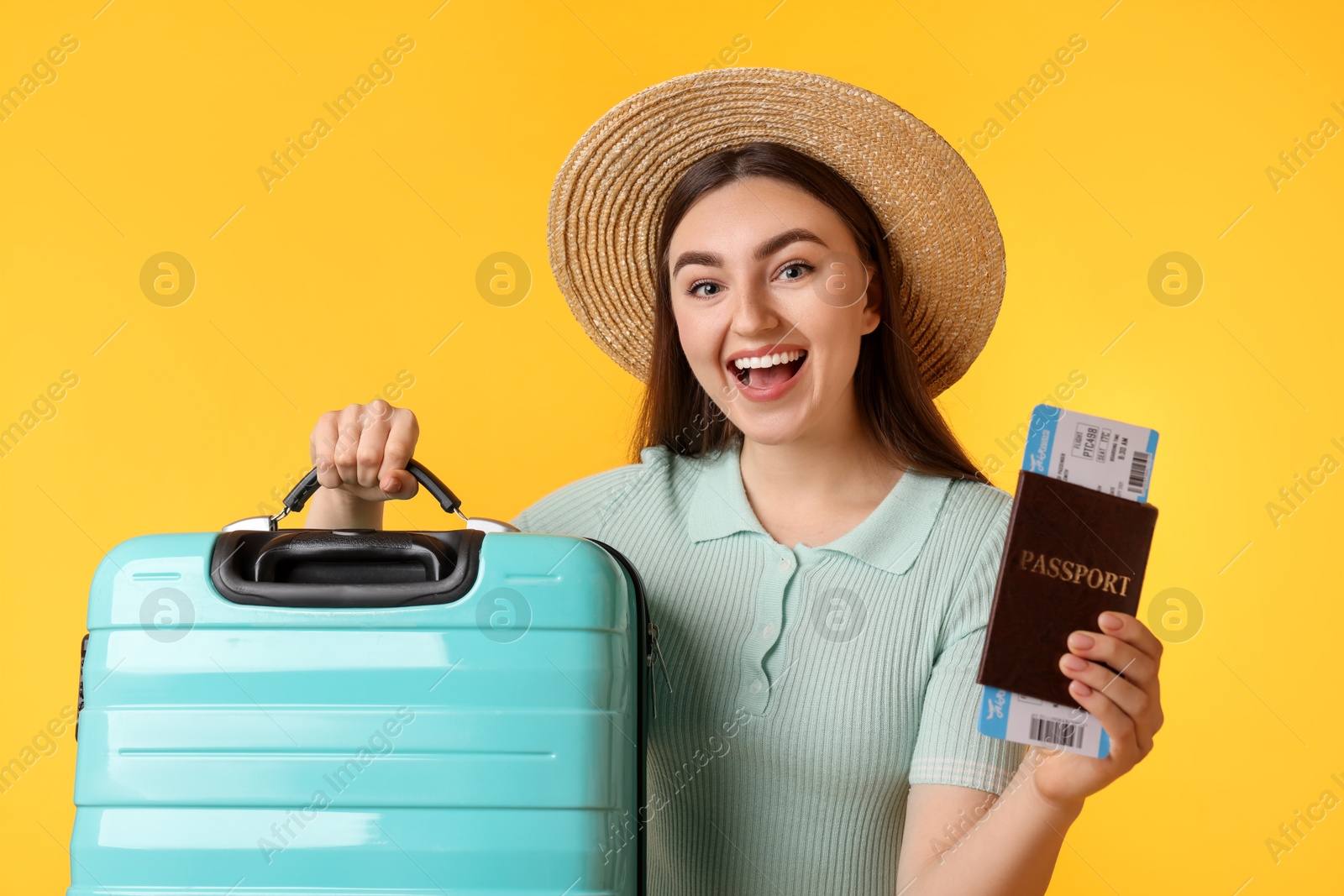 Photo of Woman in straw hat with suitcase, ticket and passport on orange background