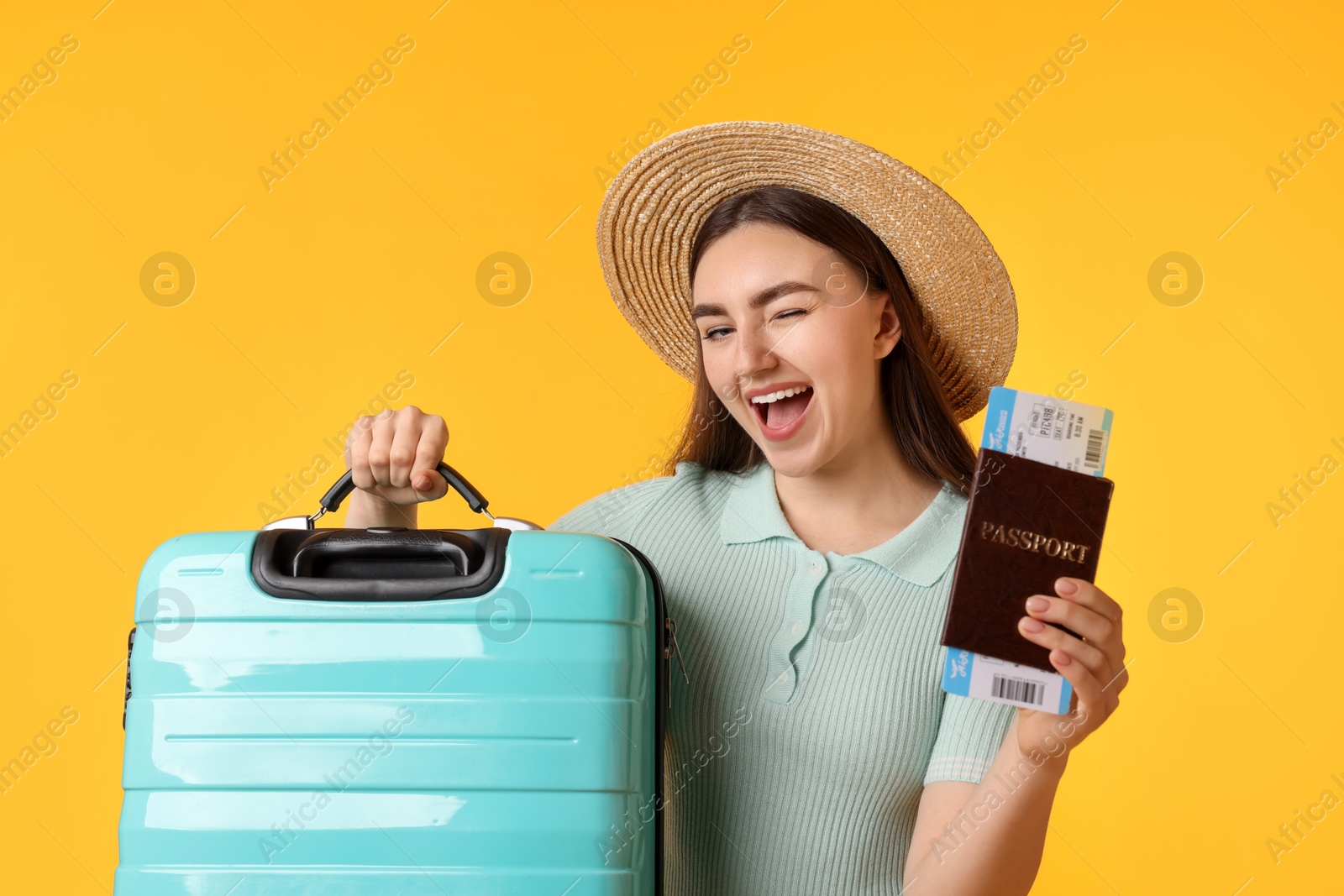 Photo of Woman in straw hat with suitcase, ticket and passport on orange background