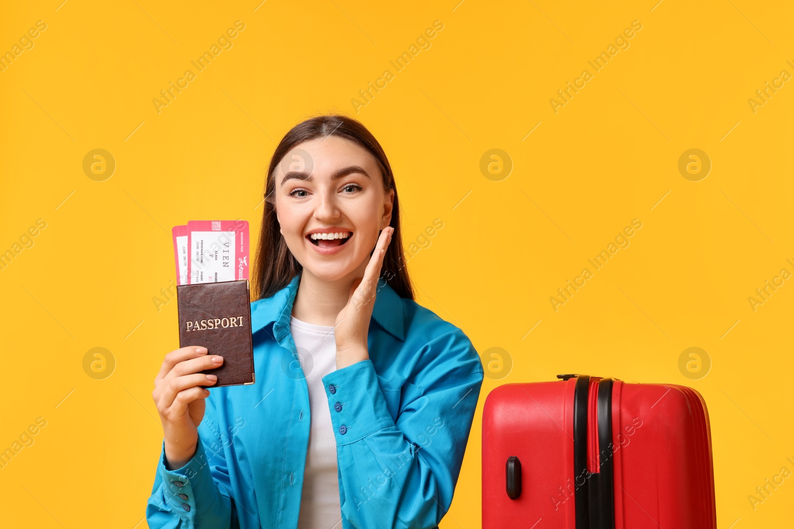 Photo of Woman with tickets, passport and suitcase on orange background