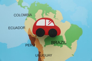 Photo of Red toy car on world map, top view. Road trip