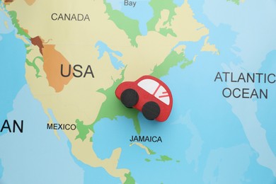 Photo of Red toy car on world map, top view. Road trip