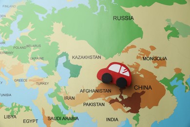 Photo of Red toy car on world map, top view. Road trip